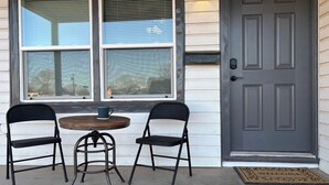 A front door with a mailbox, two chairs, a small table, and a welcome mat.