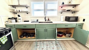 A kitchen with green cabinets, a microwave, and a sink.