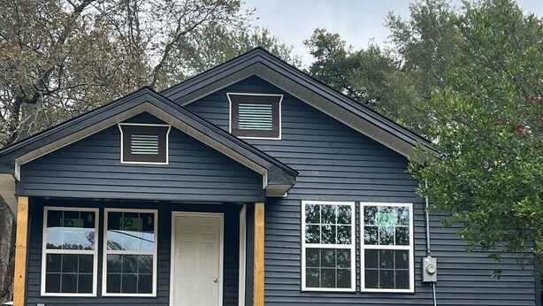 A two-story house with a front porch, a central door, and two side windows. - Huffman Extended Stay Suites (Minden)