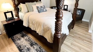 A four-poster bed with a ceiling fan, a bedside table with a lamp, and a patterned rug. - Huffman Extended Stay Suites (Minden)