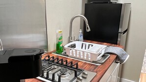 A compact kitchen with a gas stove, a sink, a microwave, and a refrigerator. - Huffman Extended Stay Suites (Minden)