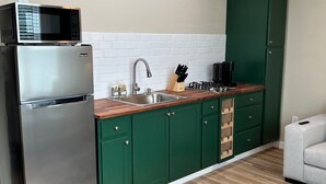 A compact kitchen with a built-in microwave, stainless steel refrigerator, and a wooden countertop. - Huffman Extended Stay Suites (Minden)