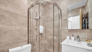 A modern bathroom with a glass-enclosed shower, a white sink, and a mirror above it.