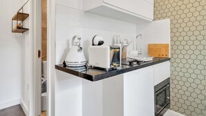 A modern kitchen with white cabinets, a black countertop, and a microwave.