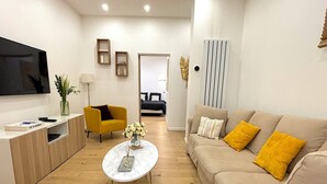 Een moderne woonkamer met een bank, fauteuil, salontafel en televisie.