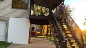 Une maison à deux étages avec un escalier en bois menant à un porche abrité.