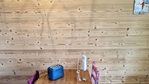 Une table en bois, un petit barbecue portable, un grille-pain et une bouilloire.