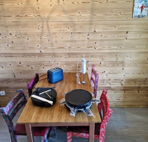 Une table en bois, un petit barbecue portable, un grille-pain et une bouilloire.