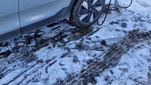 Une voiture argentée est garée à côté d’une borne de recharge, dans un environnement enneigé.