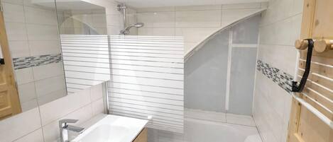 A modern bathroom with a bathtub, a shower, and a sink.