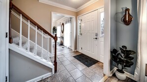 A hallway with a wooden staircase, a white door, and a potted plant. - Spacious Family Home in Franklin w/ Playground (Franklin)