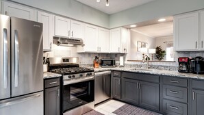 A modern kitchen with stainless steel appliances, white cabinets, and a granite countertop. - Spacious Family Home in Franklin w/ Playground (Franklin)