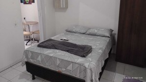 Une chambre à coucher avec un lit, une chaise, une petite table et un placard.