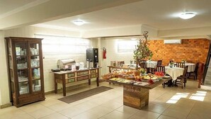 Une cuisine spacieuse dotée d’un îlot central, d’un coin repas avec chaises et tables, et d’un mur décoratif en briques.