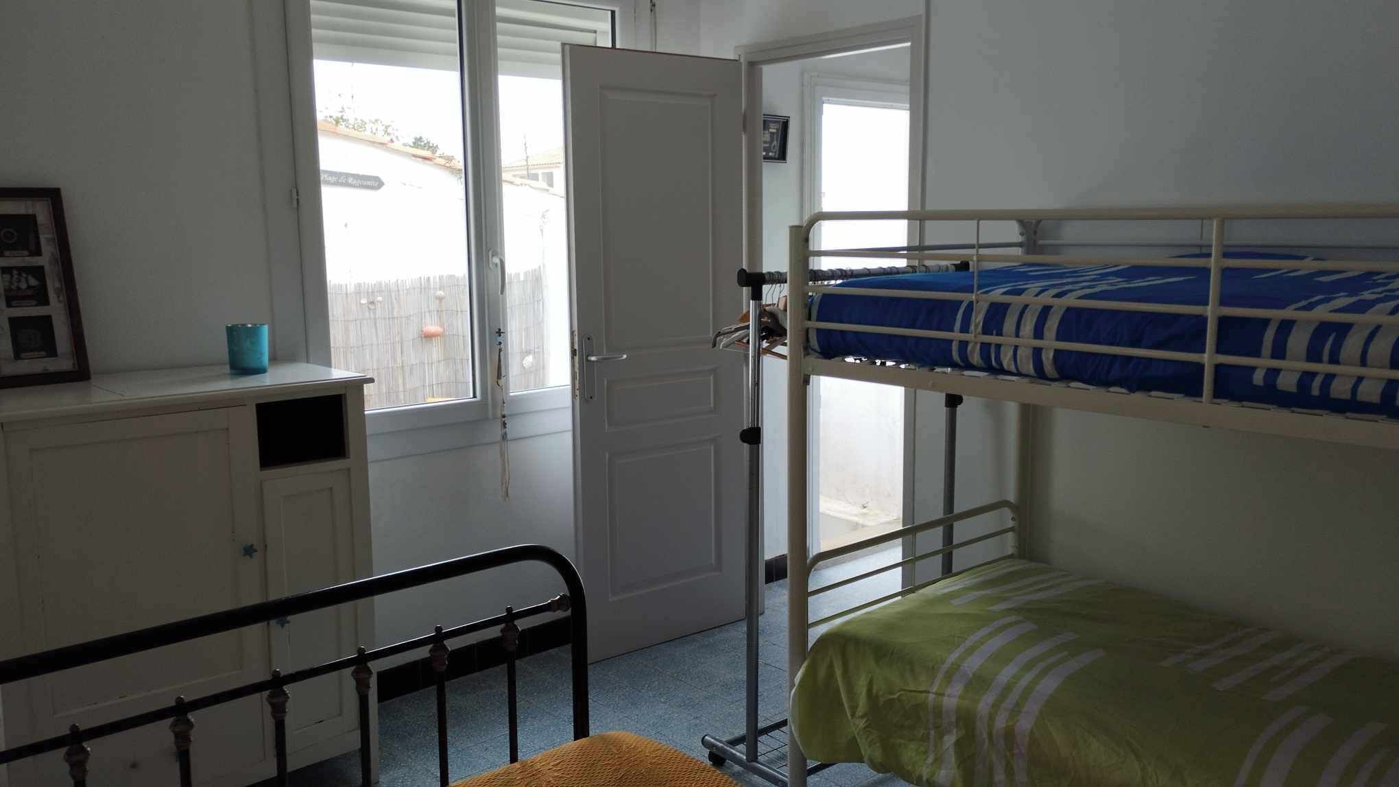 A room with bunk beds, a window, a door, and a small cabinet.
