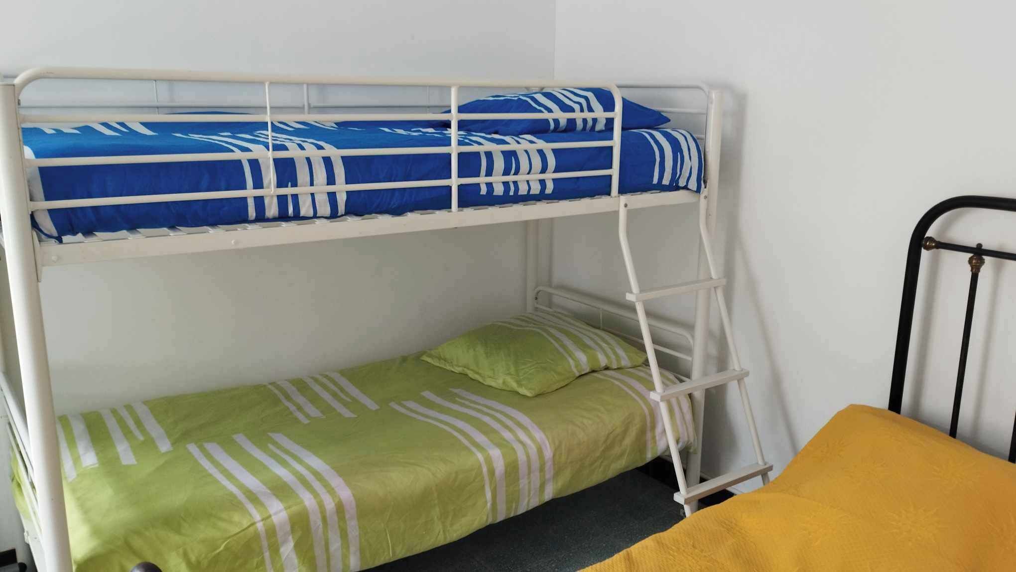 Ein Etagenbett mit zwei Schlafstellen, jeweils ausgestattet mit einer Matratze und Kissen.