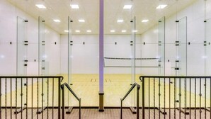 A squash court with glass walls, a central net, and metal railings. - Charming 2-bedroom townhome with fitness room, WiFi in delightful Gilbert (Gilbert)