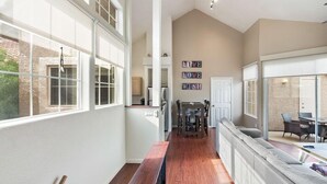 A spacious living area with a large window, a dining table, and a sofa. - Charming 2-bedroom townhome with fitness room, WiFi in delightful Gilbert (Gilbert)
