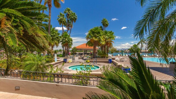 A resort pool area with palm trees, lounge chairs, and a covered pavilion. - Charming 2-bedroom townhome with fitness room, WiFi in delightful Gilbert (Gilbert)