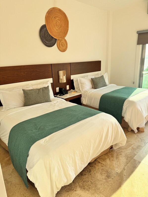A hotel room with two beds, a wooden headboard, a bedside table with a phone, and a view of the outdoors. - Hotel TamYanJa (Tamiahua)