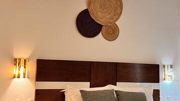 Habitación de hotel con cama, mesita de noche con teléfono, lámpara de pared y ventilador de techo.