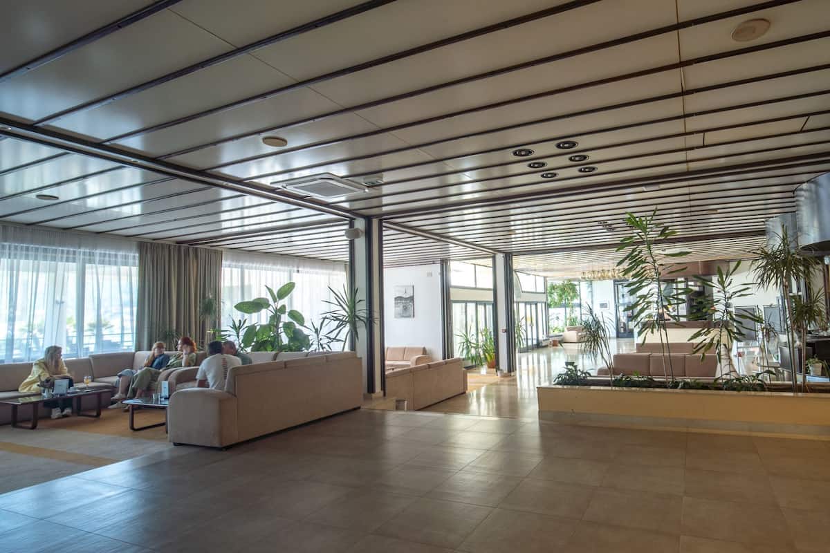 Um hall amplo com teto alto, grandes janelas e vários espaços para sentar.