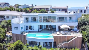 Une maison moderne à deux étages, dotée d’une piscine, d’un espace extérieur aménagé et offrant une vue sur le quartier environnant.