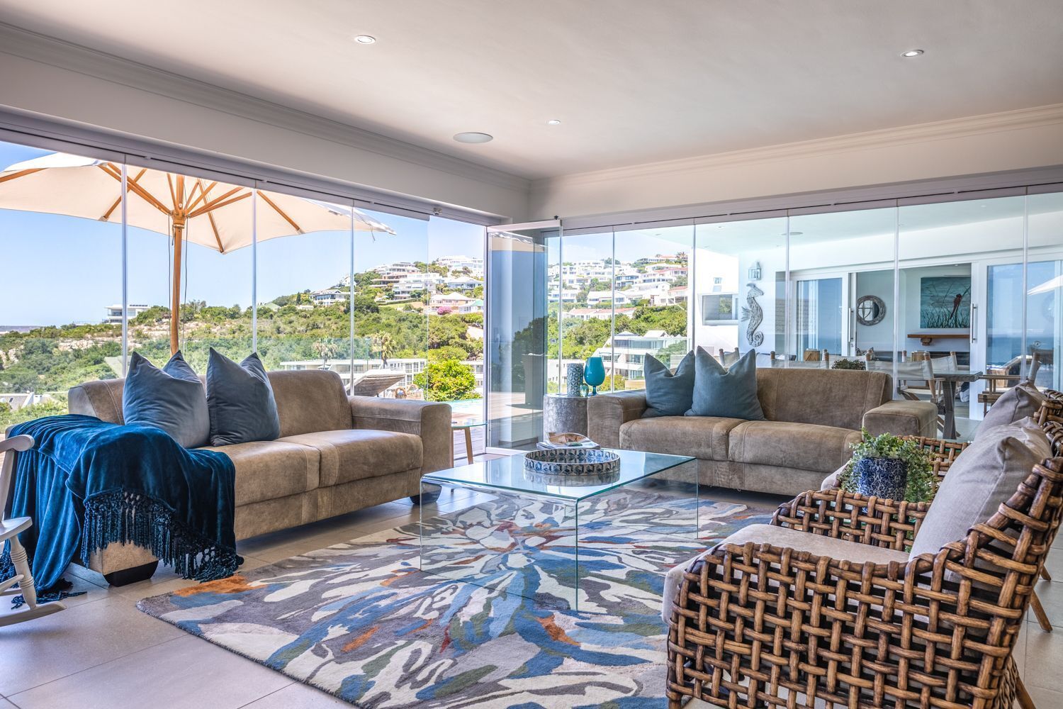 Un salon moderne avec deux canapés, une table basse en verre et une vue sur une colline.