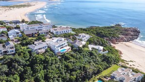 A coastal residential area with modern houses, a beach, and a rocky outcrop. - Villa Rice - Eight Bedroom Villa, Sleeps 16 (Plettenberg Bay)