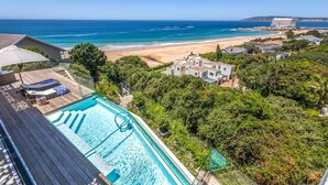 A pool with a view of the beach and ocean, surrounded by lush greenery and residential buildings. - Villa Rice - Eight Bedroom Villa, Sleeps 16 (Plettenberg Bay)