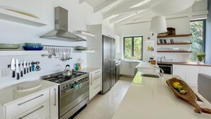 A modern kitchen with stainless steel appliances, a central island, and a view of the outdoors. - Estrella Residence - Four Bedroom Villa, Sleeps 12 (Plettenberg Bay)