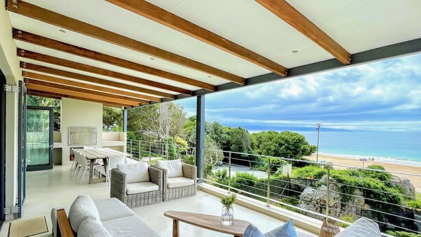 A modern living room with a large window overlooking a beach. - Estrella Residence - Four Bedroom Villa, Sleeps 12 (Plettenberg Bay)