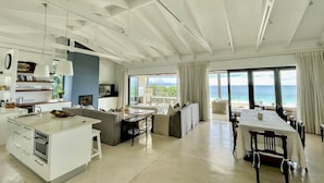 A modern kitchen with a central island, a dining area with a table and chairs, and a seating area with a sofa and chairs. - Estrella Residence - Four Bedroom Villa, Sleeps 12 (Plettenberg Bay)