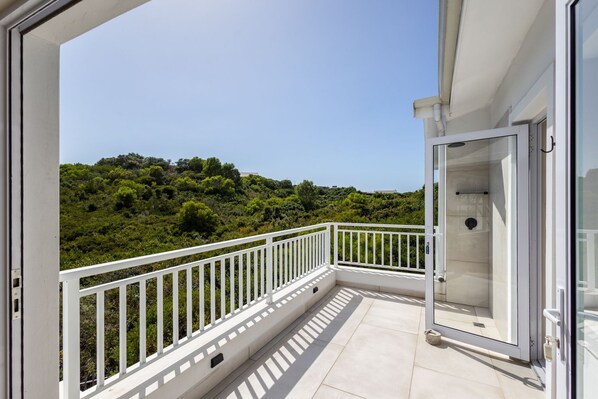A balcony with a white railing overlooking a lush green landscape.