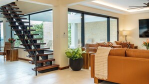 A modern living room with a staircase, a large sofa, and a potted plant.