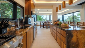 A modern kitchen with wooden cabinets, stainless steel appliances, and a large island with a marble countertop.