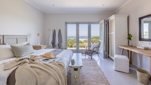 A bedroom with a large bed, a desk, and a view of the outdoors.