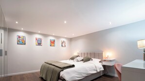 A modern bedroom with a large bed, bedside tables, a desk, and a chair. - Rock in Share - Les Ponts (Nancy)
