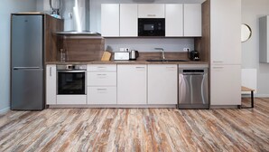 A modern kitchen with stainless steel appliances, white cabinetry, and a wooden floor. - Rock in Share - Les Ponts (Nancy)