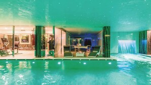 An indoor swimming pool with lounge chairs and a massage table, surrounded by glass walls and a waterfall feature. - Villa Alessandra Vista Mare (Salerno)
