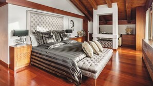 A bedroom with a large bed, a sofa, a nightstand, a mirror, and a wooden ceiling. - Villa Alessandra Vista Mare (Salerno)