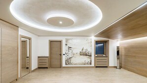 A modern interior with a circular skylight, wooden flooring, and a large cityscape painting on the wall. - Villa Alessandra Vista Mare (Salerno)