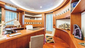 A modern, curved wooden reception desk with a telephone, a notepad, and a lamp. - Villa Alessandra Vista Mare (Salerno)