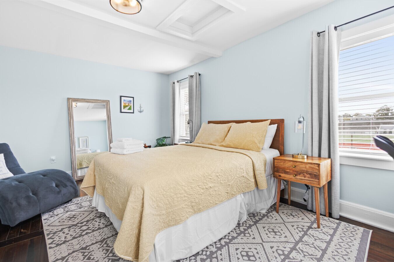 A bedroom with a bed, bedside table, and a window with blinds.