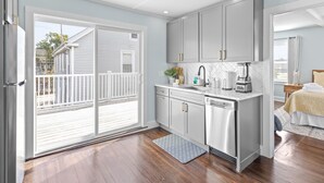 A modern kitchen with grey cabinets, a dishwasher, and a countertop with a coffee maker and other appliances.