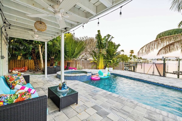 A covered outdoor area with a pool, seating, and potted plants.