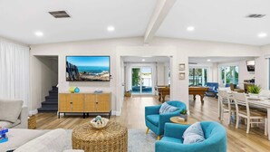 A spacious living area with a sofa, armchairs, a dining table, and a view of the ocean through large windows. - 4 Master Suites, Heated Pool, Game Room, King Beds (Indian Rocks Beach)