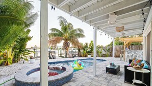 A covered outdoor area with a hot tub, lounge chairs, and a pool. - 4 Master Suites, Heated Pool, Game Room, King Beds (Indian Rocks Beach)