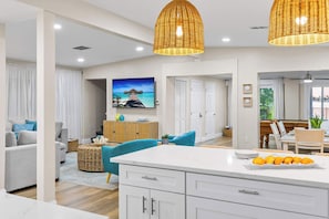 A modern kitchen with white cabinetry, a central island, and a dining area with a wooden table and chairs.