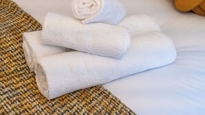 A neatly made bed with white towels and a woven blanket. - Cozy Studio in Central Locale with Kitchenette (London)